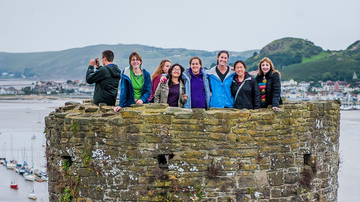 Students on castle tower in front of lake