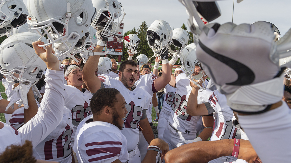 Raider Football players cheer and raise throwback helments