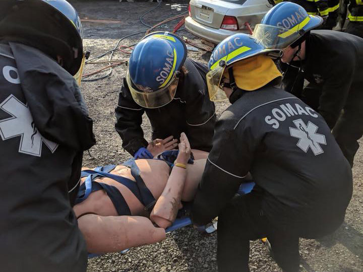 SOMAC volunteers lift a stretcher with a dummy on it