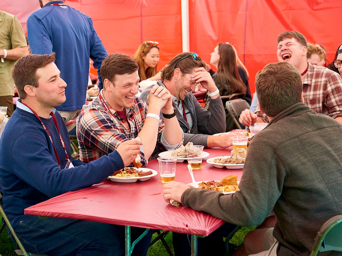 Alumni laugh while sharing a meal in a Reunion tent.