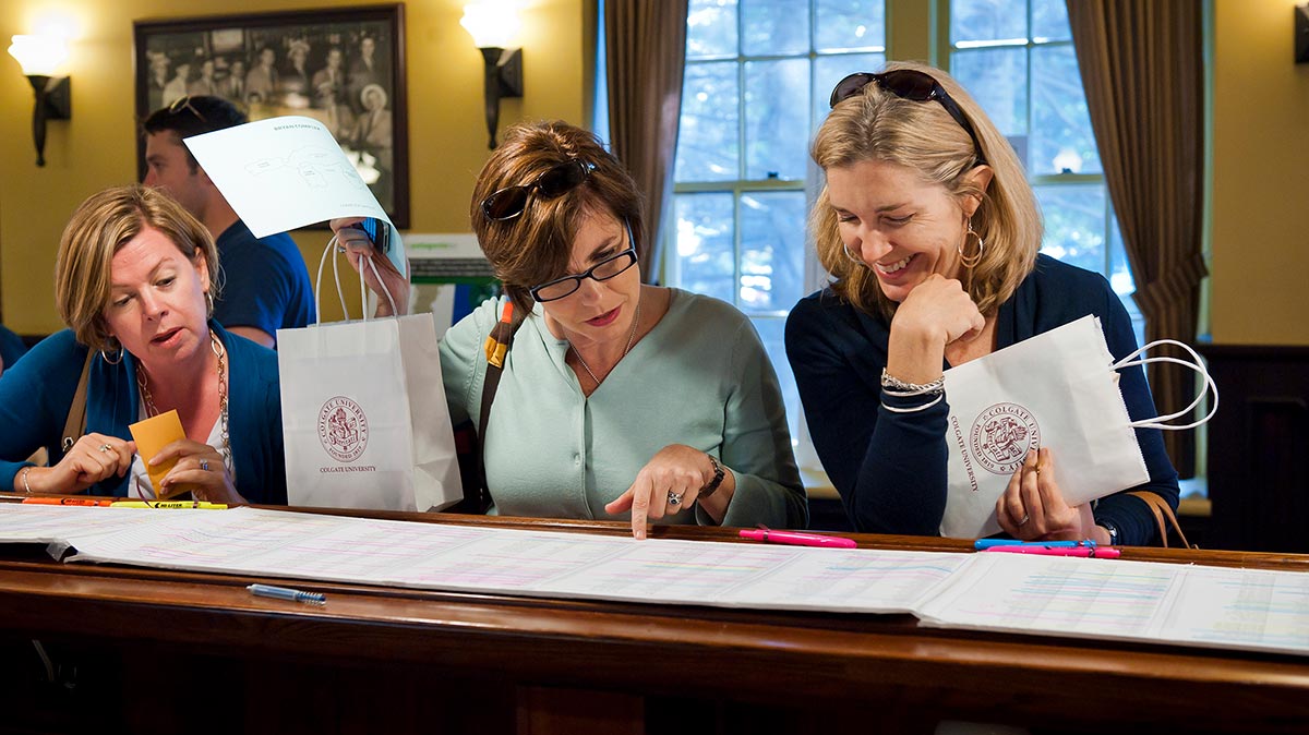 Three alumnae review the Reunion attendee list at the Donovan's Pub welcome center