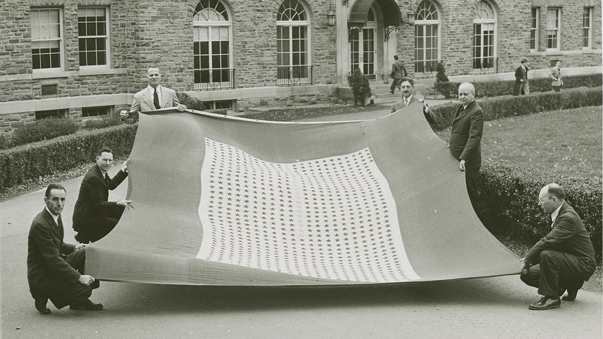 Individuals hold a banner of stars on the Academic Quadrangle in front of Lawrence Hall